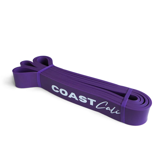 A rolled up purple exercise band with the text 'COAST Cali' printed on it.