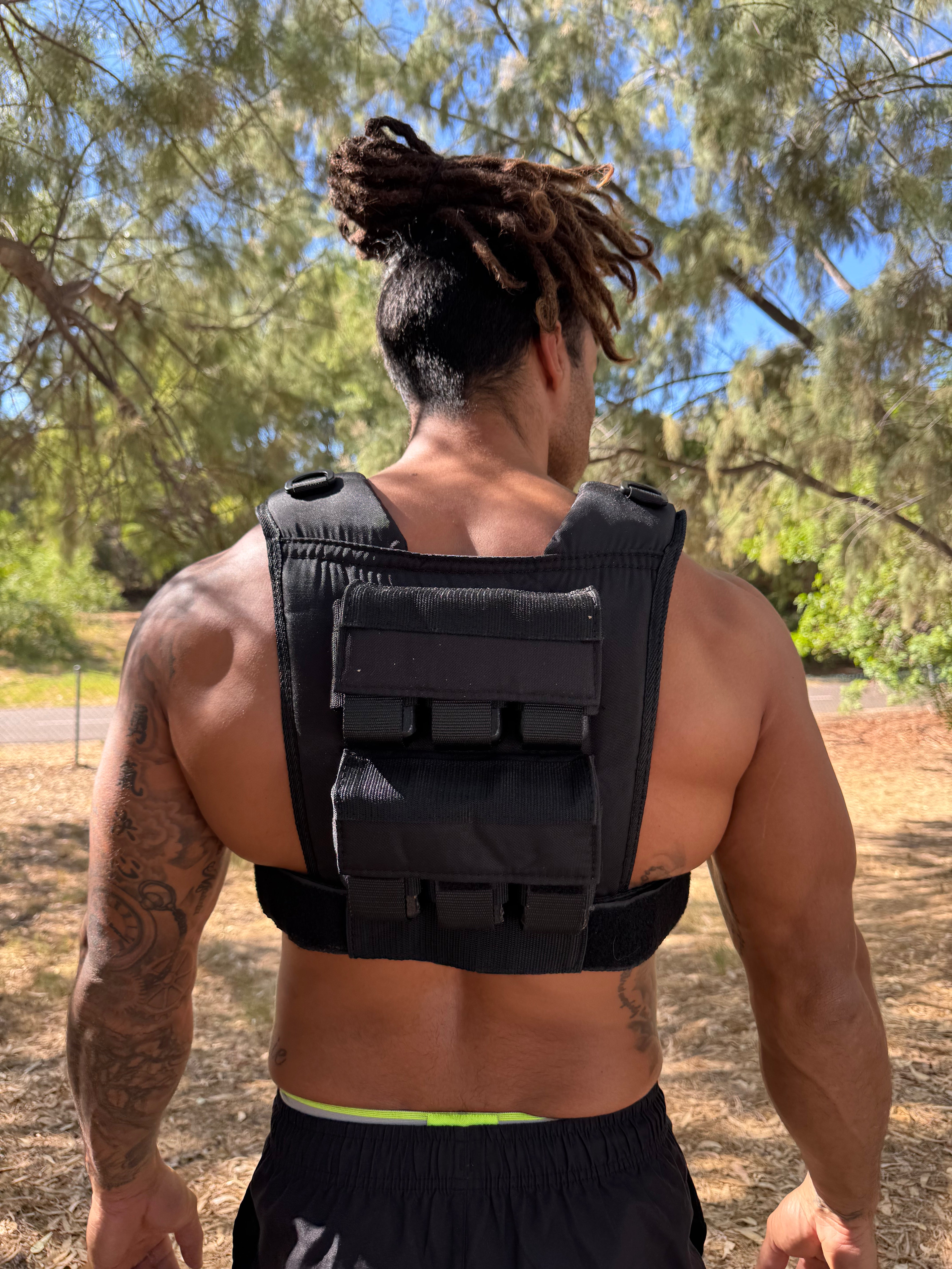 Person wearing a black weighted vest outdoors with trees in the background