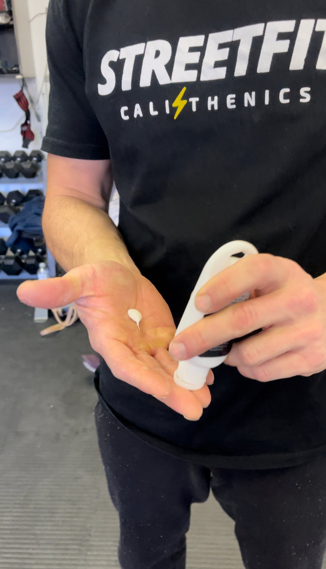 A close up of a man applying liquid chalk to his hands for a workout