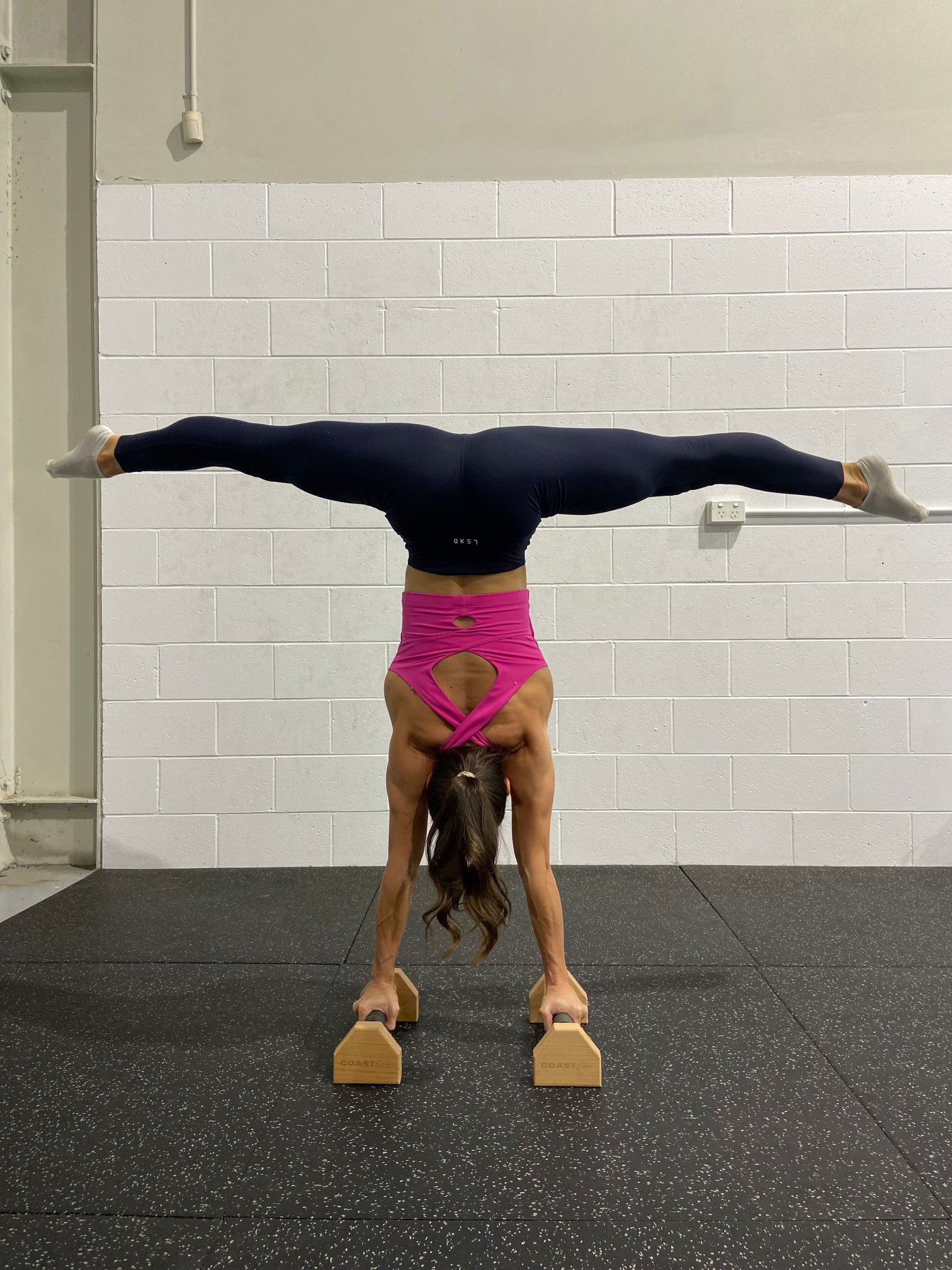 A woman doing a handstand on a set of parallettes