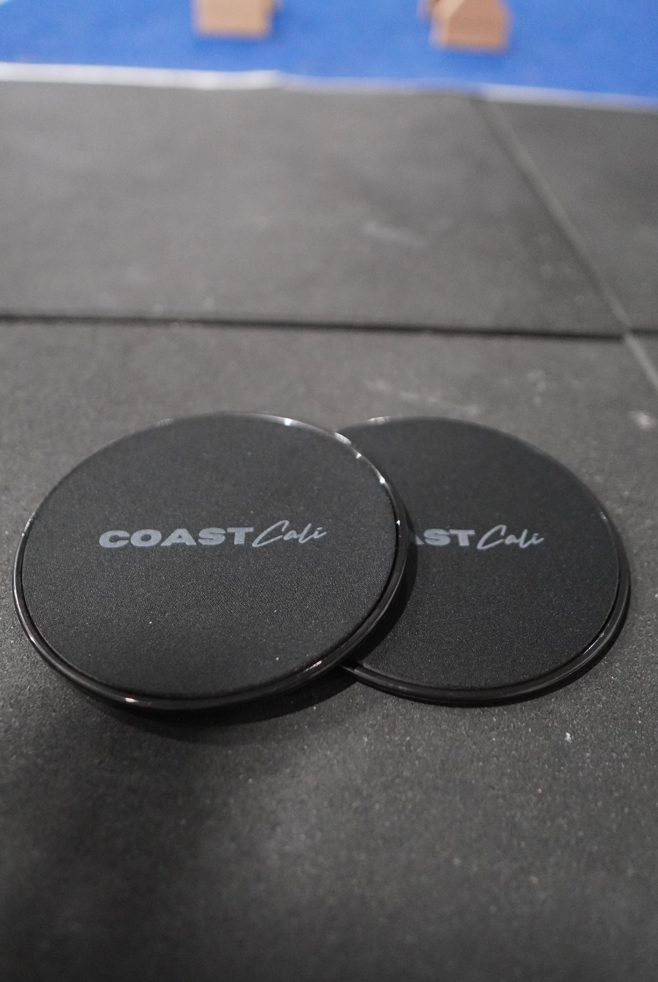 Two black gymnastics sliders with the logo 'COAST Cali' on the top surface.