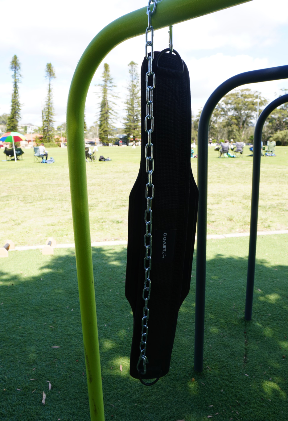 Dip belt hanging over a bar at an outdoor gym