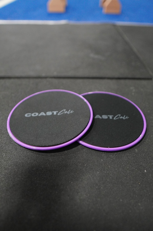 Two purple gymnastics sliders with the logo 'COAST Cali' on the top surface.