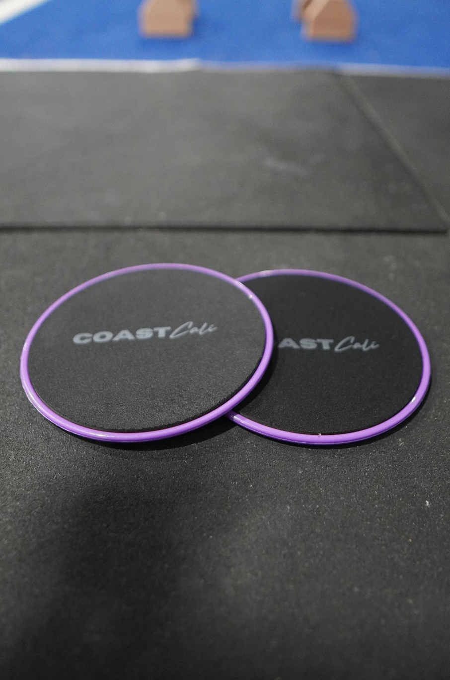 Two purple gymnastics sliders with the logo 'COAST Cali' on the top surface.