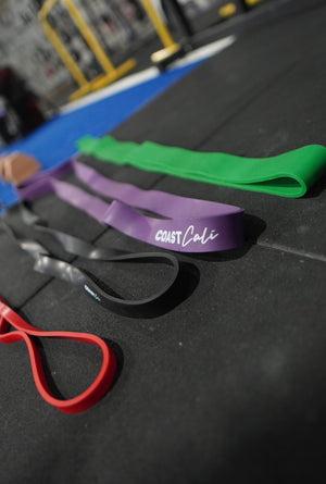 A set of 4 resistance bands on a black gym floor