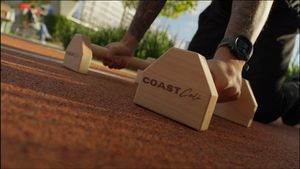 Person using wooden parallettes with 'Coast Cali' branding