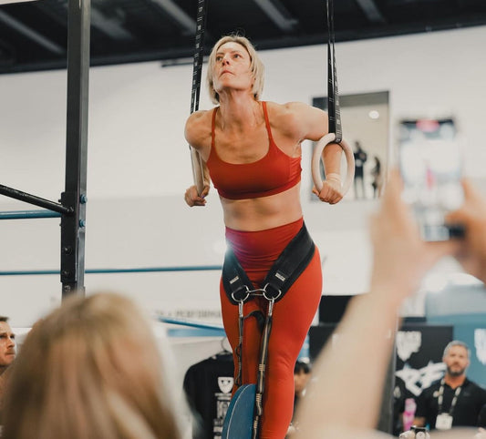 woman doing a weighted muscle up on gymnastics rings