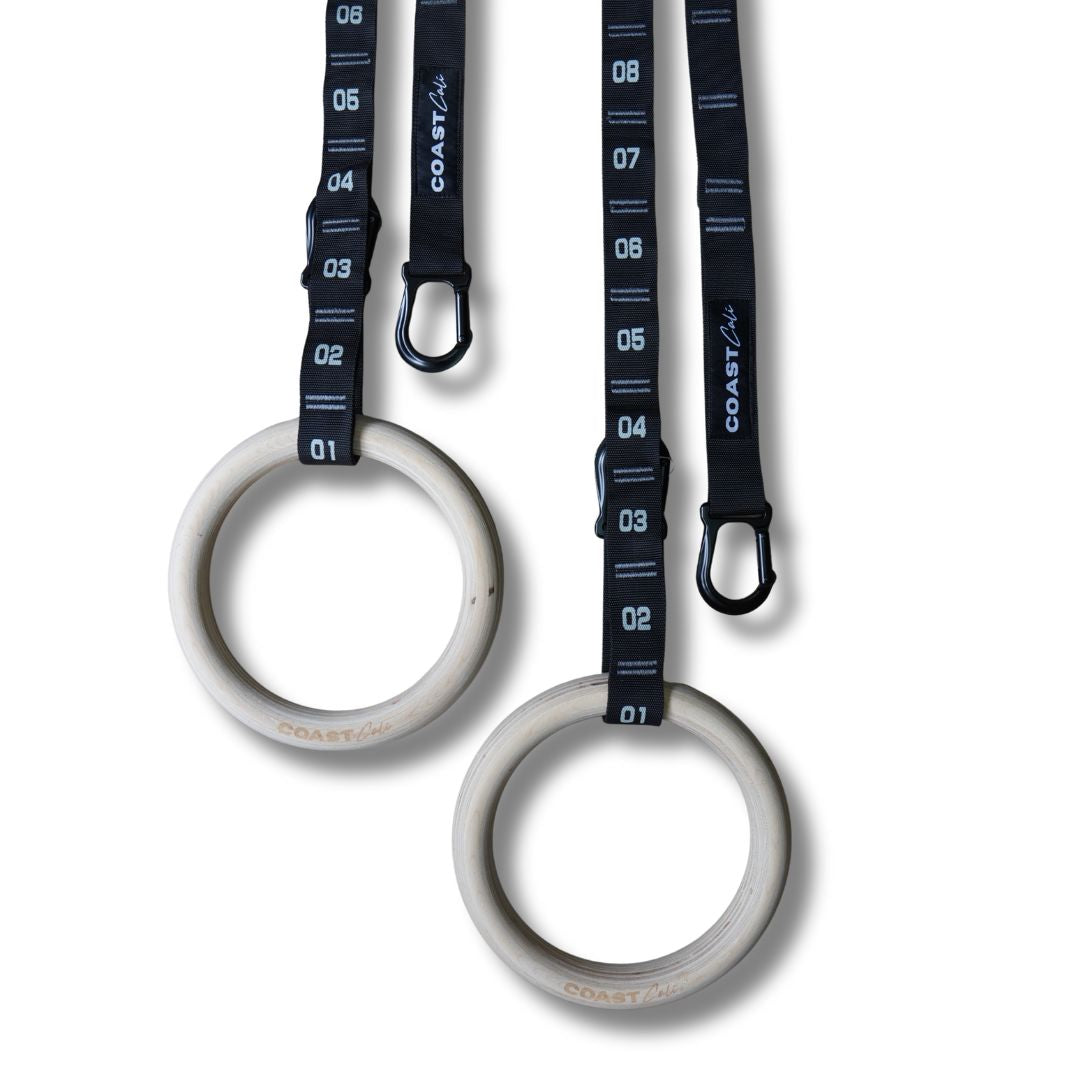 Two white gymnastic rings with black straps and measurement markings on a white background.