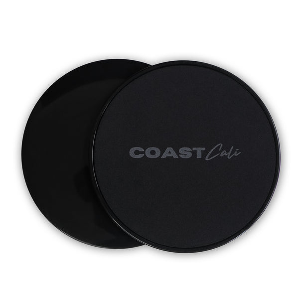 Two black gymnastics sliders with the logo 'COAST Cali' on the top surface.
