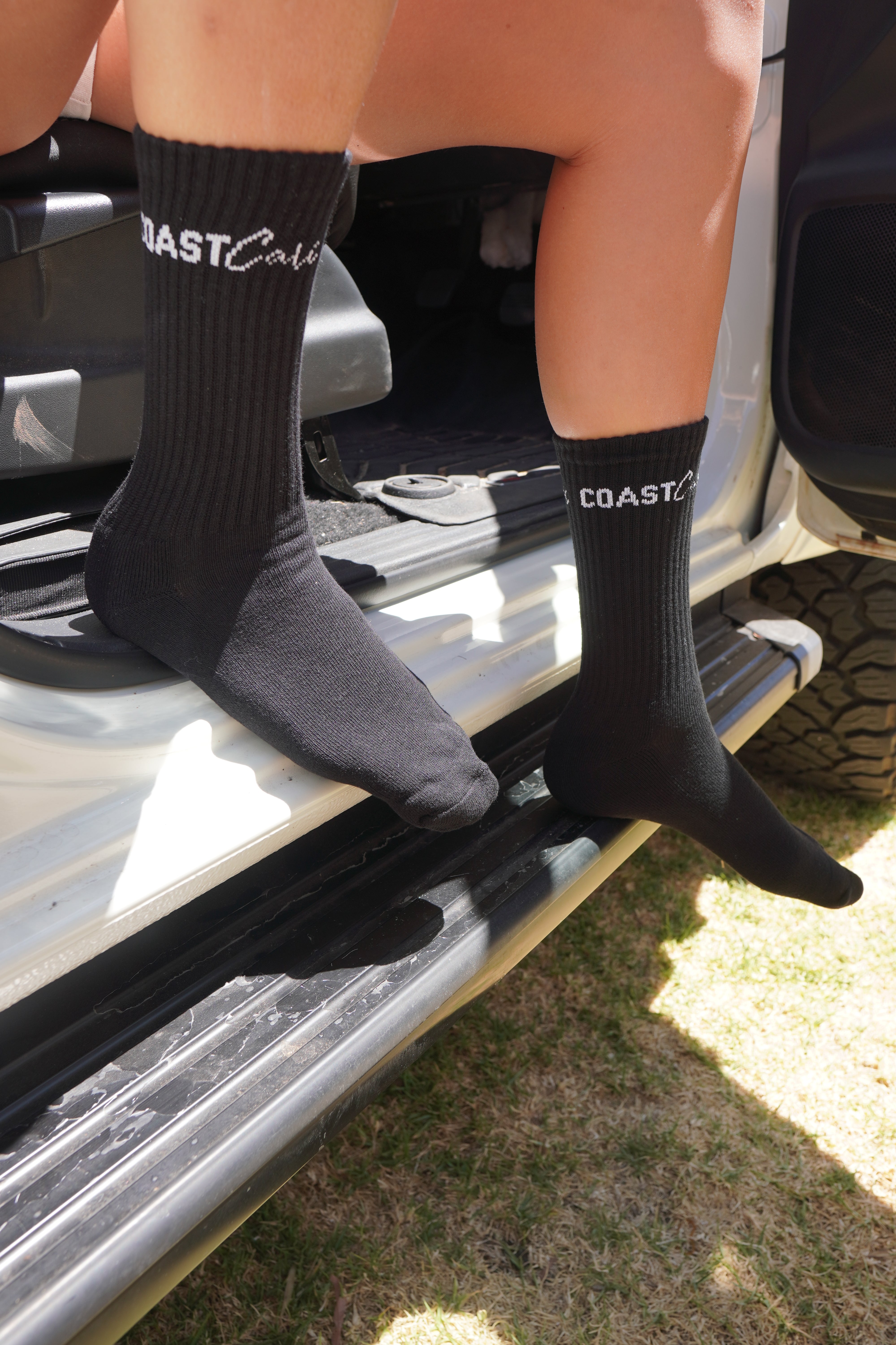 A woman wearing black socks sitting on the edge of a car