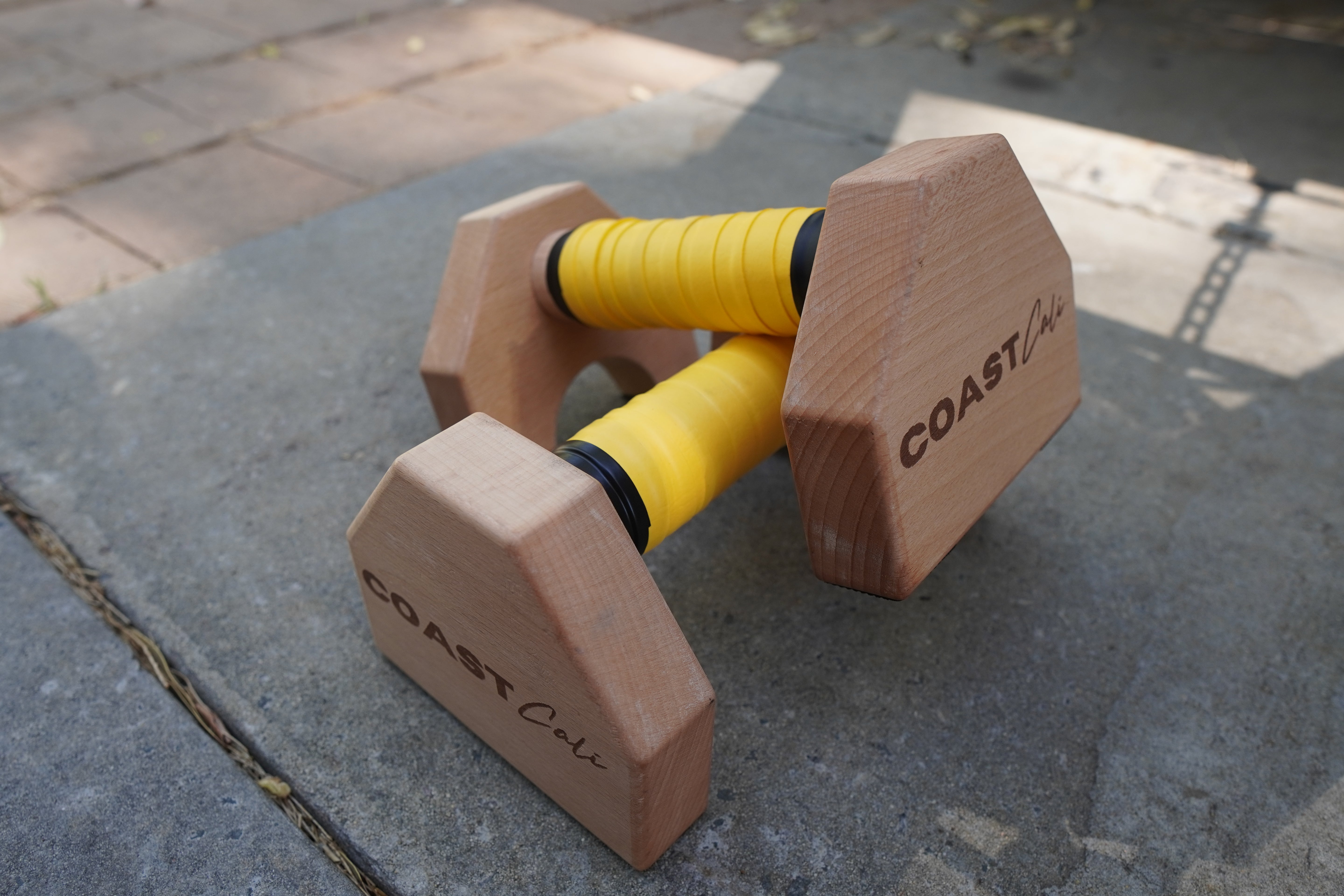 A pair of parallettes with yellow grip tape