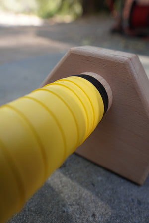 A close up of yellow grip tape on parallettes