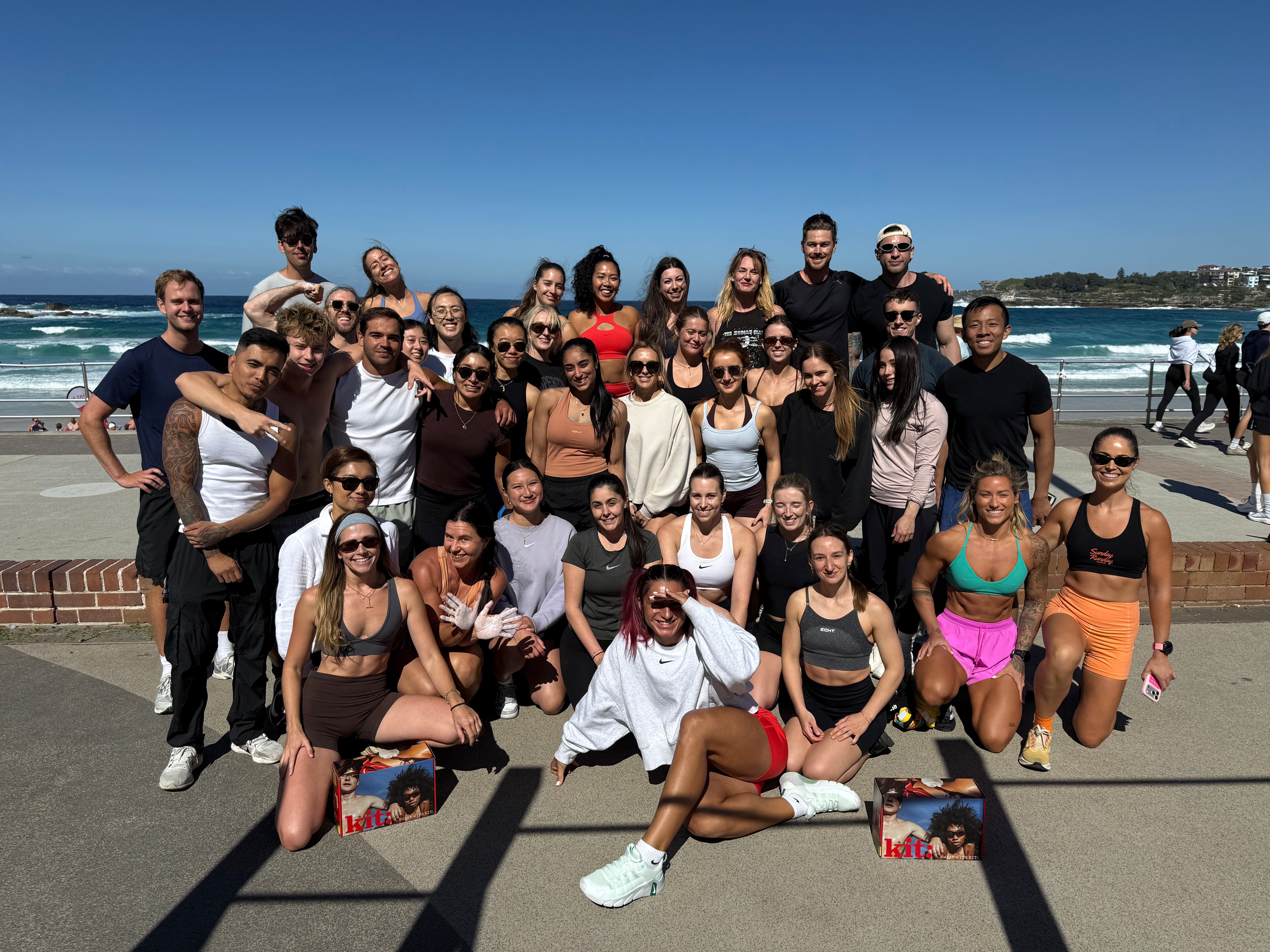 Group of people posing for a photo on a beach with ocean and clear sky in the background