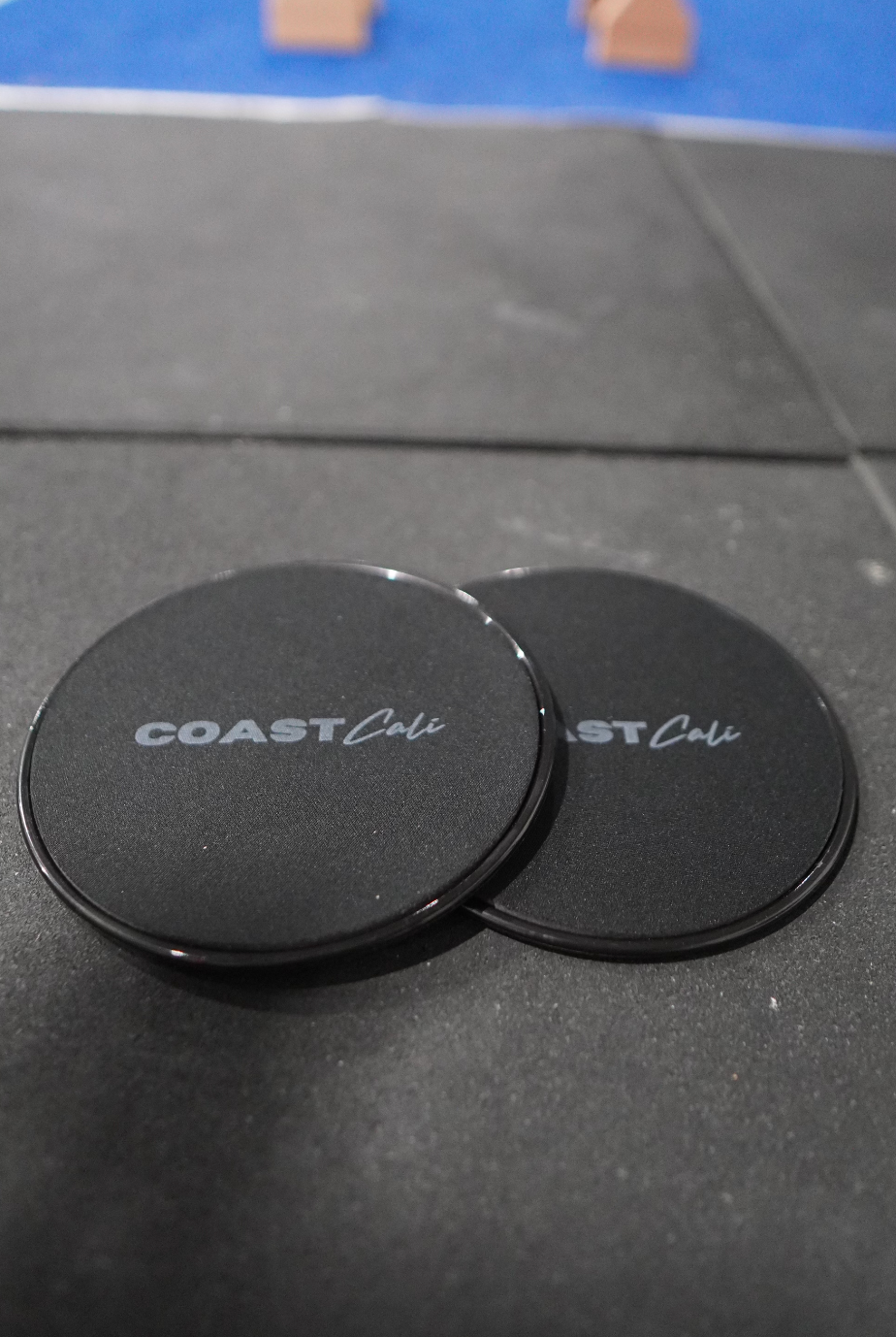 Two black gymnastics sliders with the logo 'COAST Cali' on the top surface.