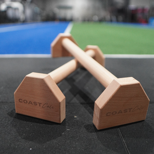 A close up of gymnastics parallettes with a gym in the background
