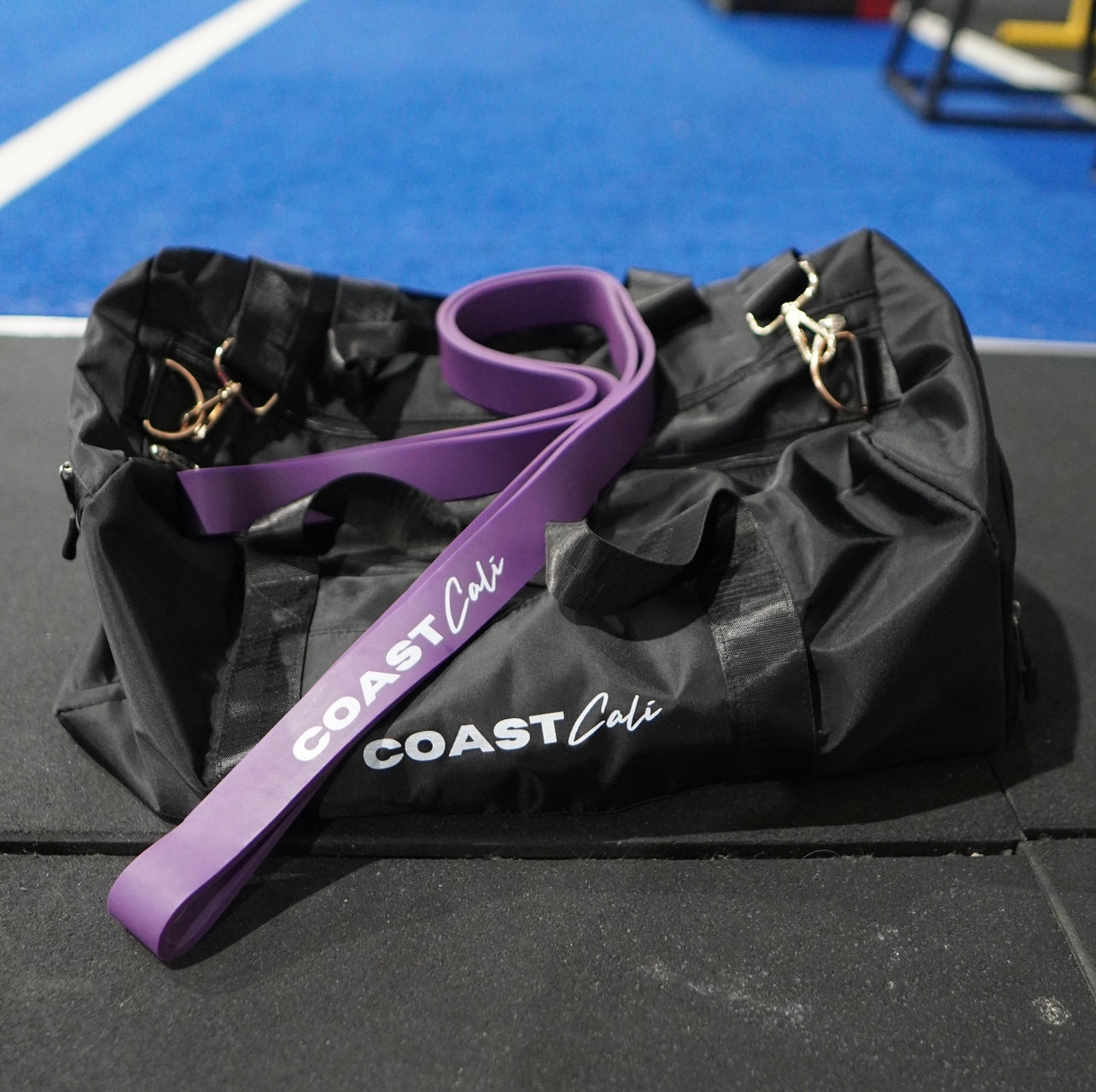 A purple resistance band on a black duffle bag